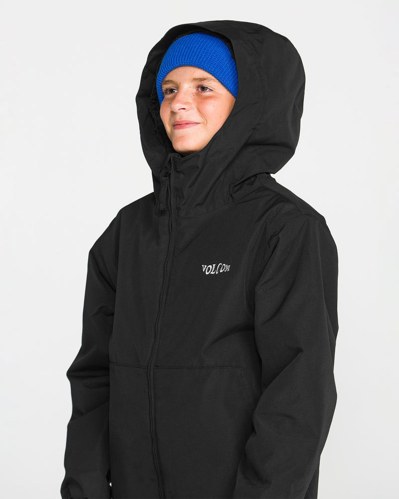 A person wears the Volcom Kids’ Youth Chaos Insulated Jacket in black, featuring recycled insulation and the VOLCOM logo on the chest, paired with a bright blue beanie. They smile slightly against a plain white background, showcasing this reliably weather-resistant outerwear.