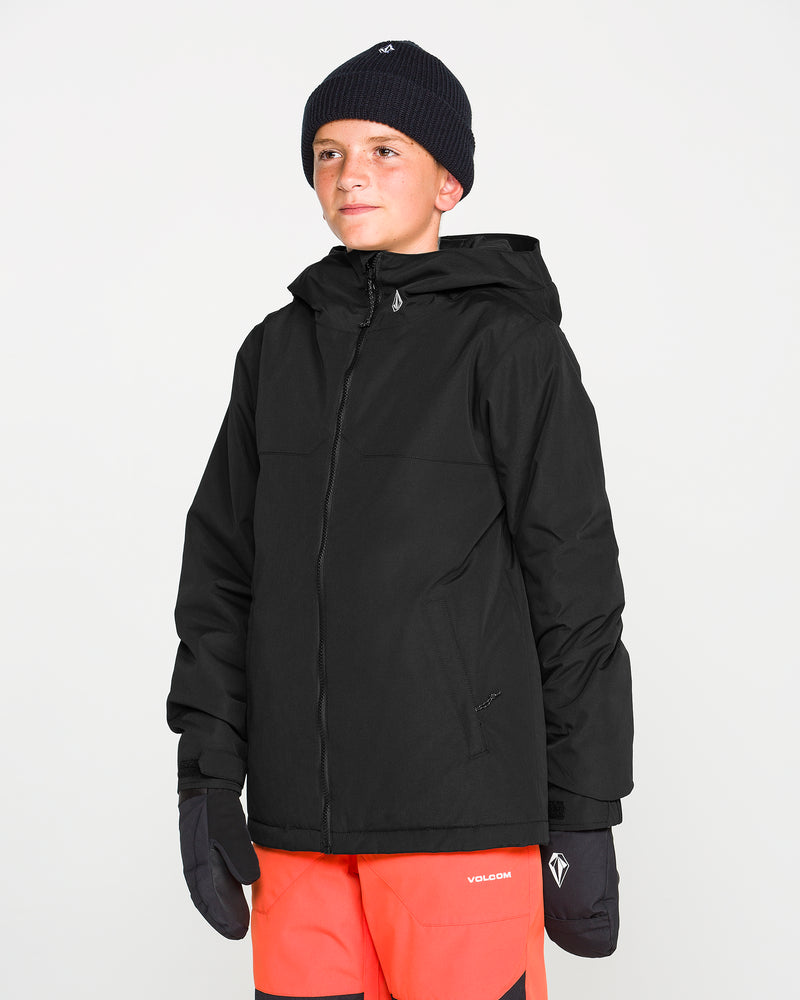 A young person wearing the Volcom Kids’ Youth Stone.91 Insulated Jacket in black, paired with a black beanie, black gloves, and bright orange pants, stands against a plain white background, looking slightly to the side with a subtle smile.