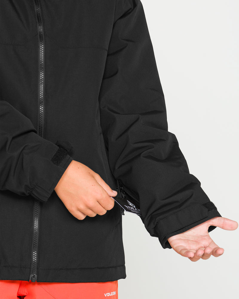 A person wearing a black Volcom Kids’ Youth Stone.91 Insulated Jacket made with recycled insulation and red pants is pulling up the sleeve with one hand to reveal the inside of the cuff. The image is cropped to focus on the torso and arms only.