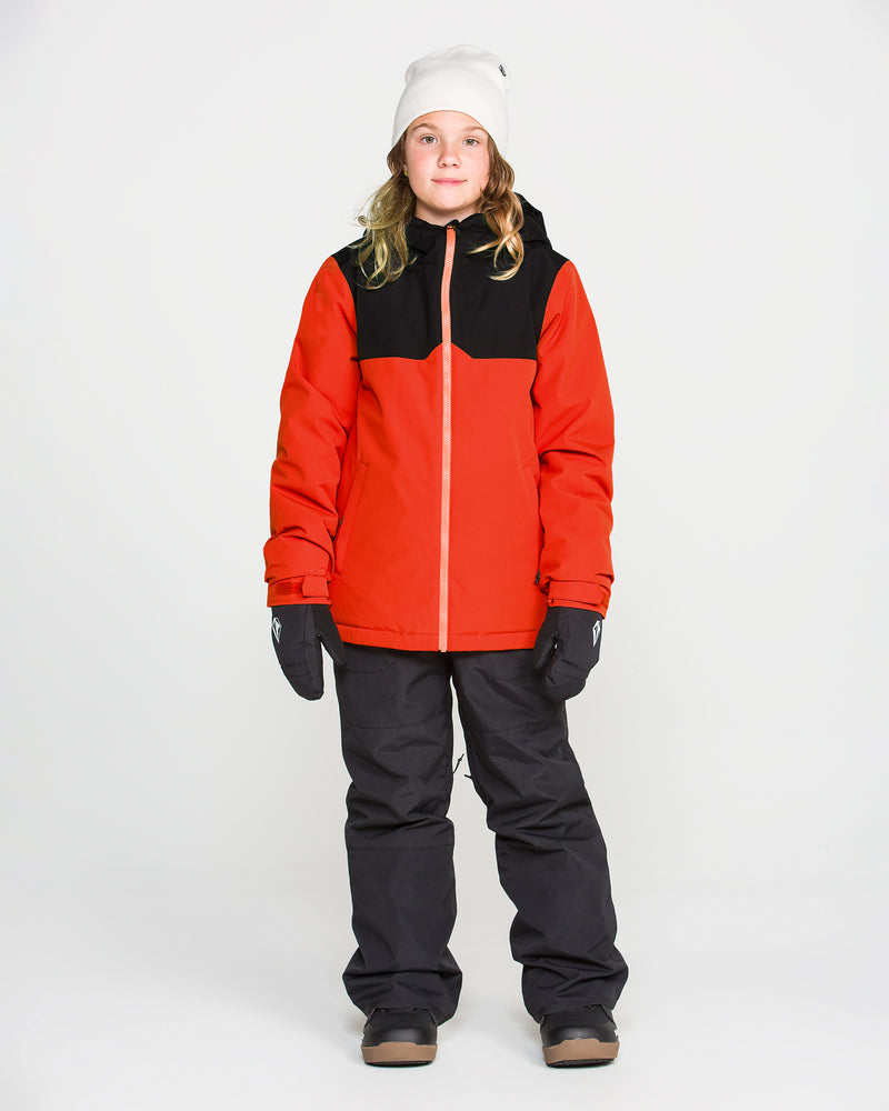 A person wearing the Volcom Kids’ Youth Stone.91 Insulated Jacket in red and black with recycled insulation, paired with black snow pants, black gloves, brown boots, and a white beanie, stands against a plain white background.