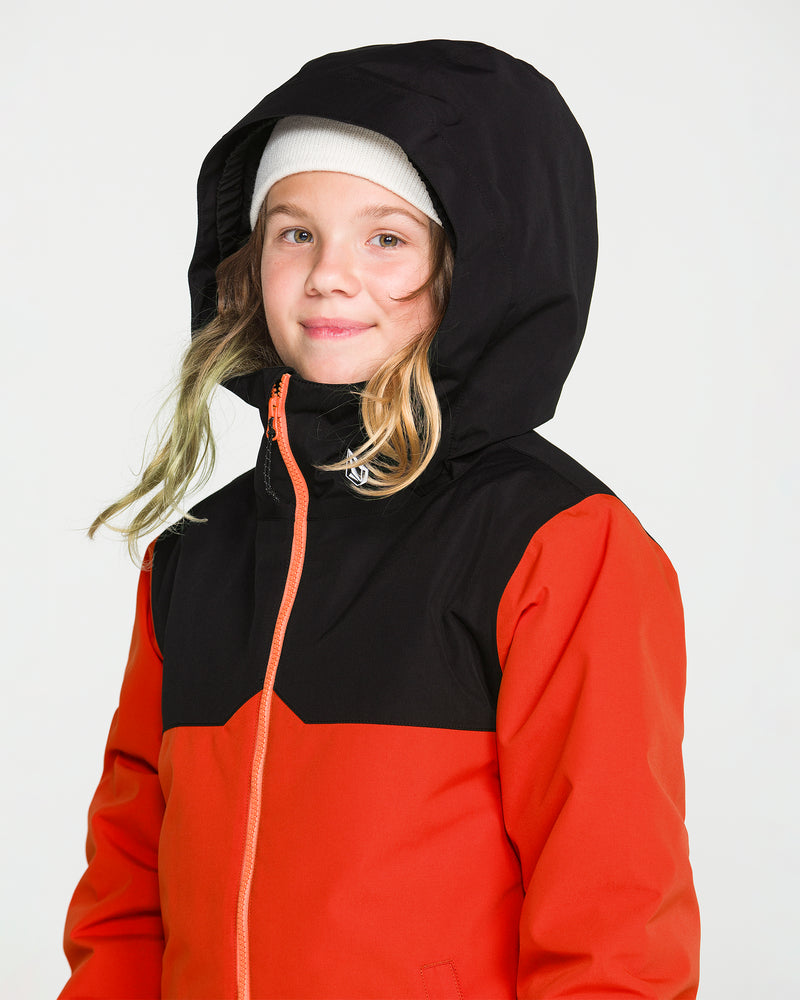 A young child wearing the Volcom Kids’ Youth Stone.91 Insulated Jacket in red and black, which features recycled insulation, along with a white beanie, looks at the camera with a slight smile against a plain background.