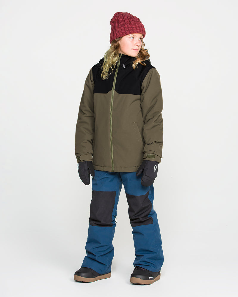 A person wearing a red knit beanie, Volcom Kids’ Youth Stone.91 Insulated Jacket in olive and black with recycled insulation, blue and black snow pants, gloves, and boots stands against a plain white background, looking to the side.