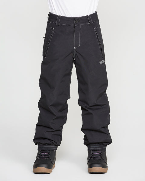 A person stands against a plain white background wearing Volcom Kids’ Youth Chaos Insulated Pants in black with recycled insulation, black winter boots, and a white shirt.