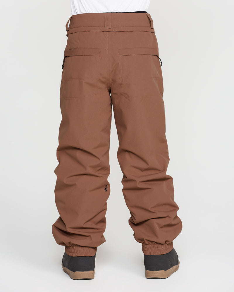 A child is shown from the back against a plain white background, wearing the Volcom Kids’ Youth Chaos Insulated Pants in brown. The pants feature V-Science 2-Layer construction and recycled insulation, have pockets and elastic cuffs at the ankles, and are paired with black boots.