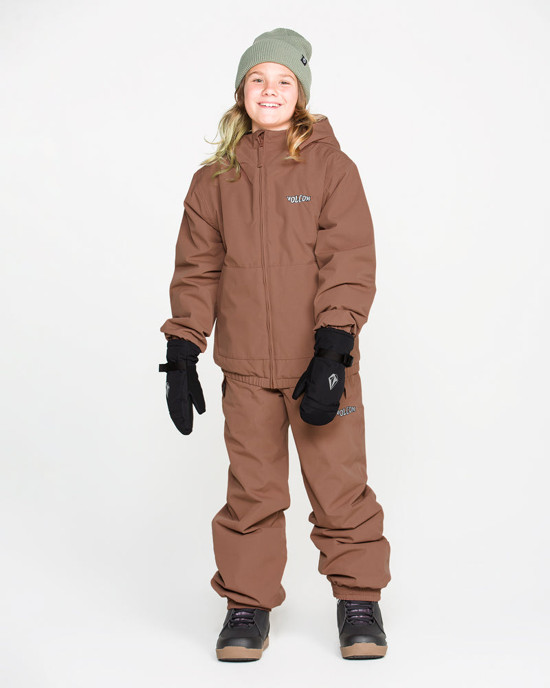 A smiling child wearing a brown winter jacket and Volcom Kids’ Youth Chaos Insulated Pants, which feature V-Science 2-Layer fabric and recycled insulation, paired with black gloves, gray boots, and a light green beanie, stands against a plain white background.