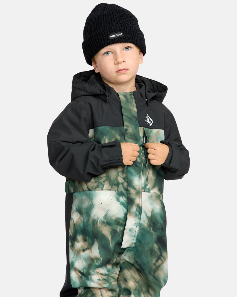 A young child wears the Kids' Little Flurry One Piece snowsuit and a black beanie, standing with hands holding the front of the jacket against a plain light background.
