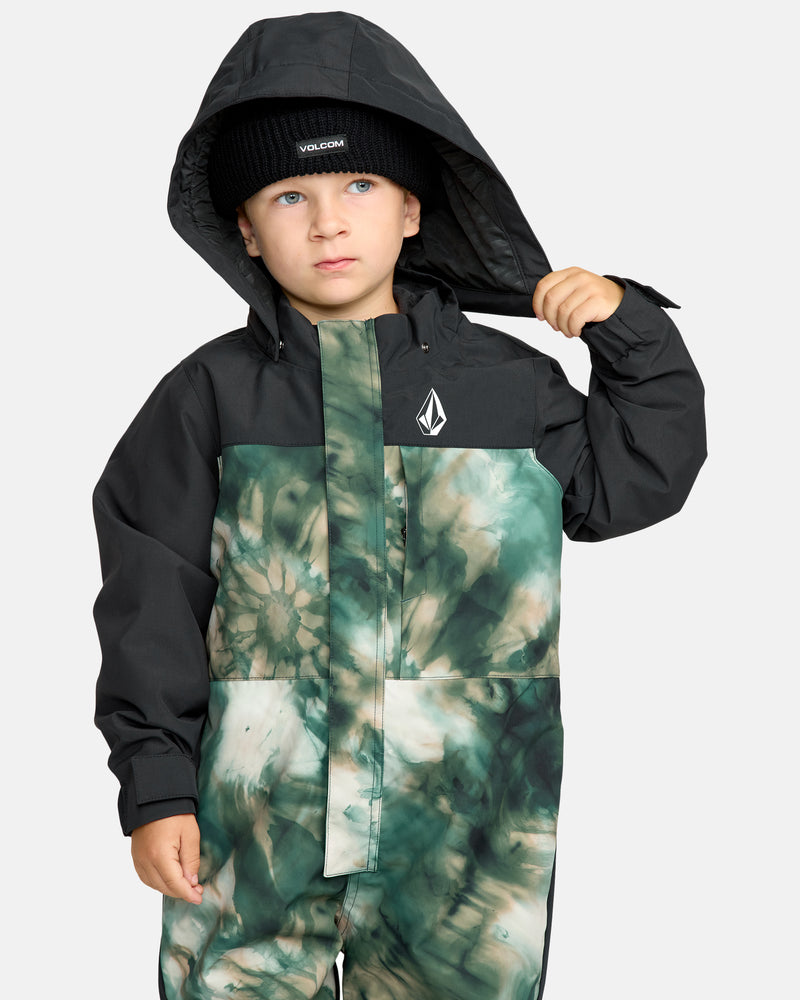 A young child wears the Kids' Little Flurry One Piece, featuring a black hood and beanie with VOLCOM logo, and a green and white tie-dye pattern on the front, looking to the side while lifting the hood.