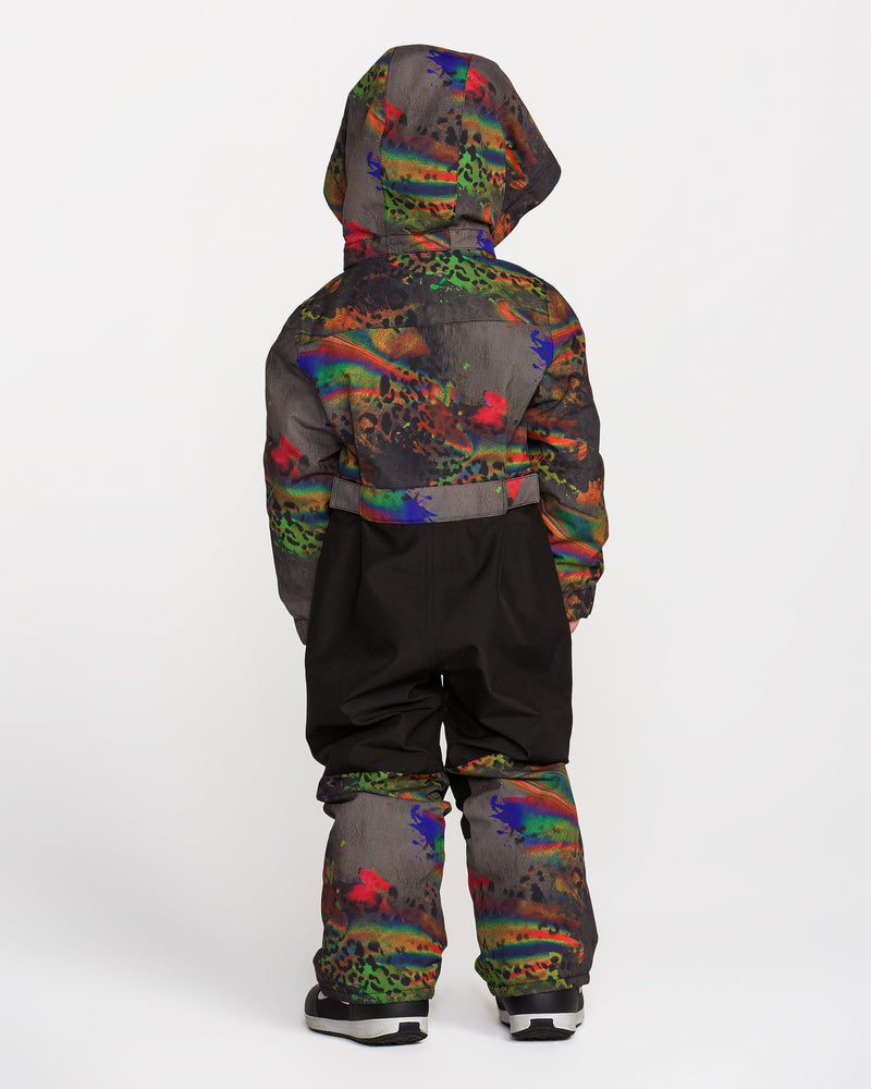 A child is seen from behind wearing the Volcom Kids’ Little Flurry One Piece—a hooded snowsuit adorned with colorful patterns, designed with cozy insulation and a helmet-compatible removable hood—set against a plain white background.
