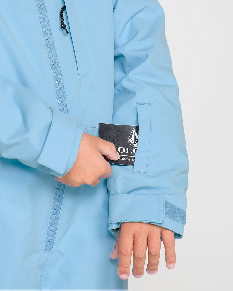 Wearing Volcom’s Kids’ Little Flurry One Piece in light blue, a person places a card into the small sleeve pocket, their other hand resting nearby.