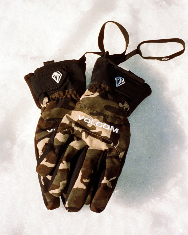Volcom Men’s V.Co Nyle camo-print gloves with wrist straps and logo detailing resting on snow, featuring Thinsulate warmth.