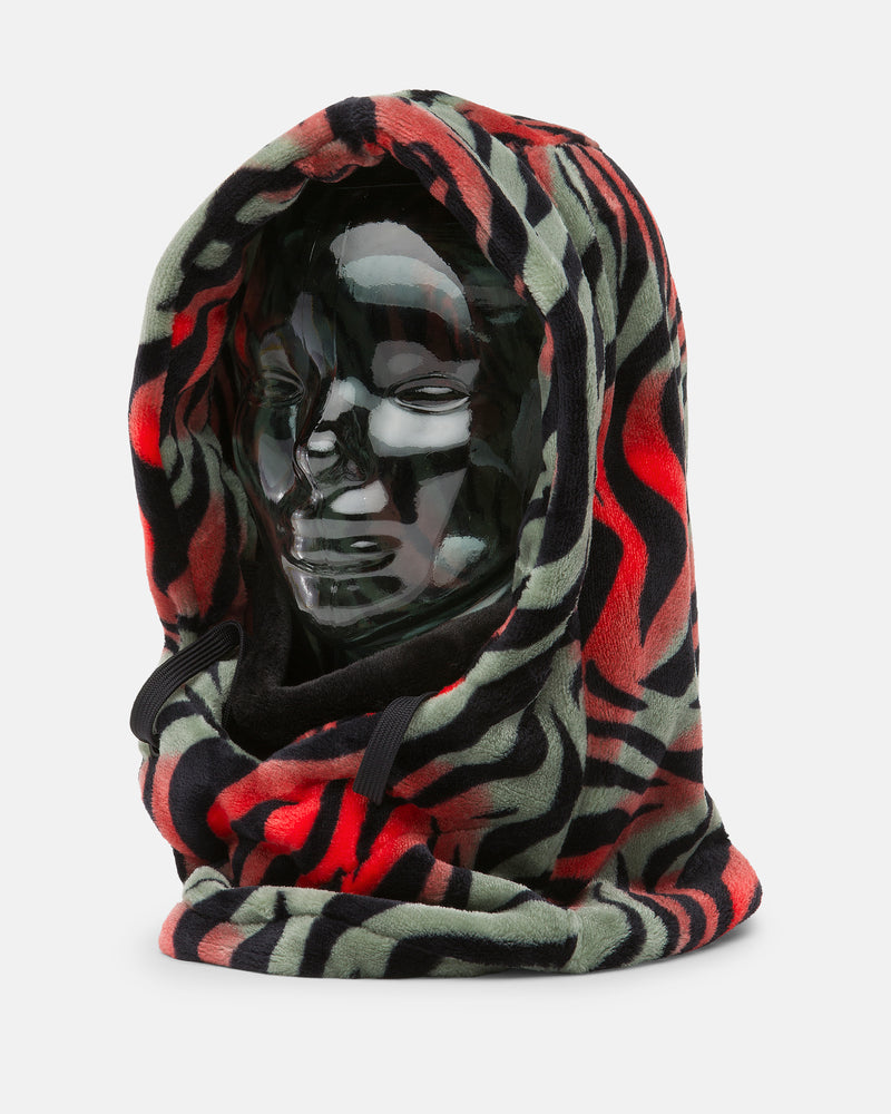 A shiny, black mannequin head is wearing the Volcom Women’s Dang Hood, a fleece hooded scarf featuring a bold red, black, and green abstract pattern that covers the head and neck as a cozy neck warmer—perfect for cold weather.