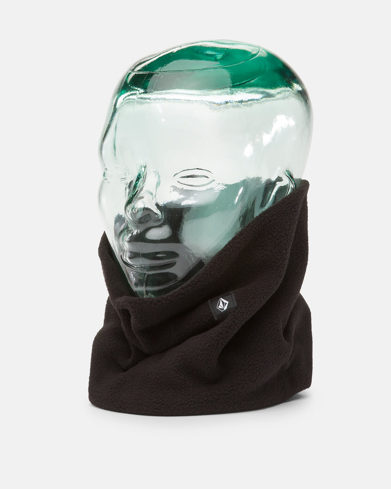 A glass mannequin head displays the Volcom Women’s V.Scout Neckband, a black polyester fleece accessory designed for added warmth, featuring a small logo tag on the front. The plain white background highlights this cozy neck gaiter from Volcom.