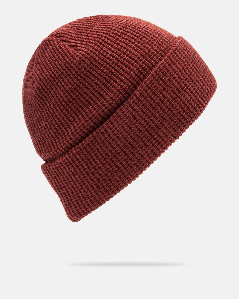 The Volcom Women’s Power Beanie in maroon acrylic, featuring a folded brim, is displayed against a plain white background. The beanie appears to be floating with a faint shadow beneath it.