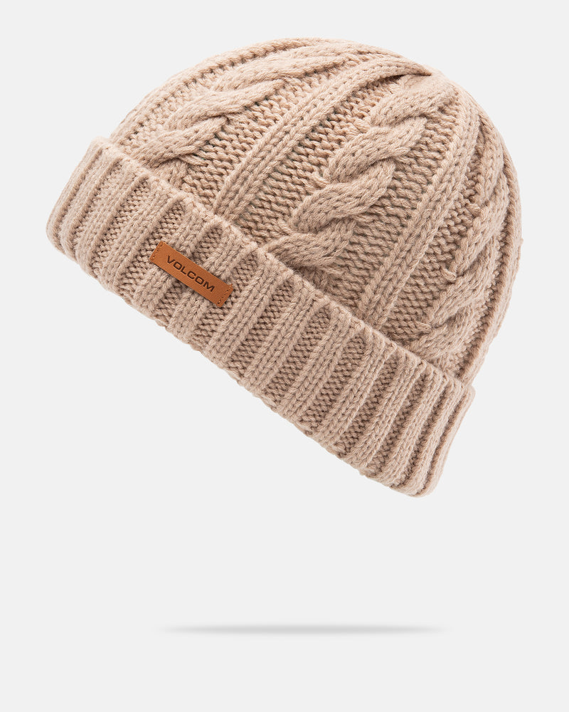 The Women’s Stone Knit Beanie by Volcom is a beige cable-knit hat with a folded brim and a small brown Volcom logo tag. This stylish beanie is shown on a white background with a gentle shadow beneath it.