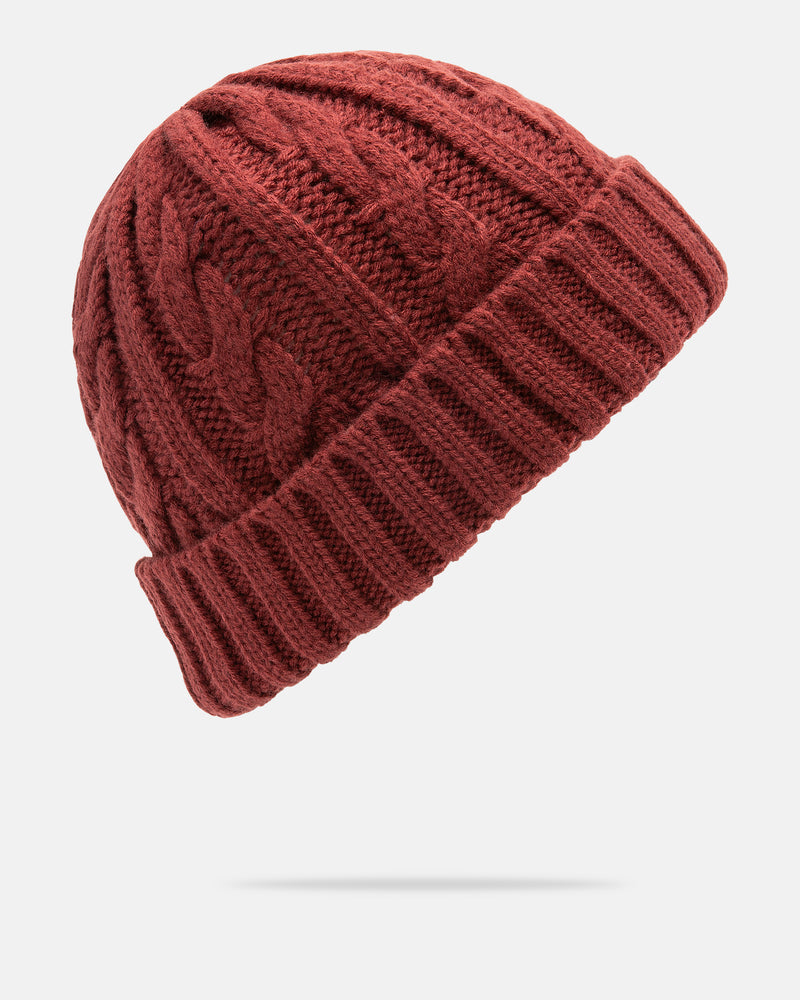 The Volcom Women’s Stone Knit Beanie features a classic cable knit pattern in red with a folded ribbed cuff, designed for women and displayed on a plain white background.