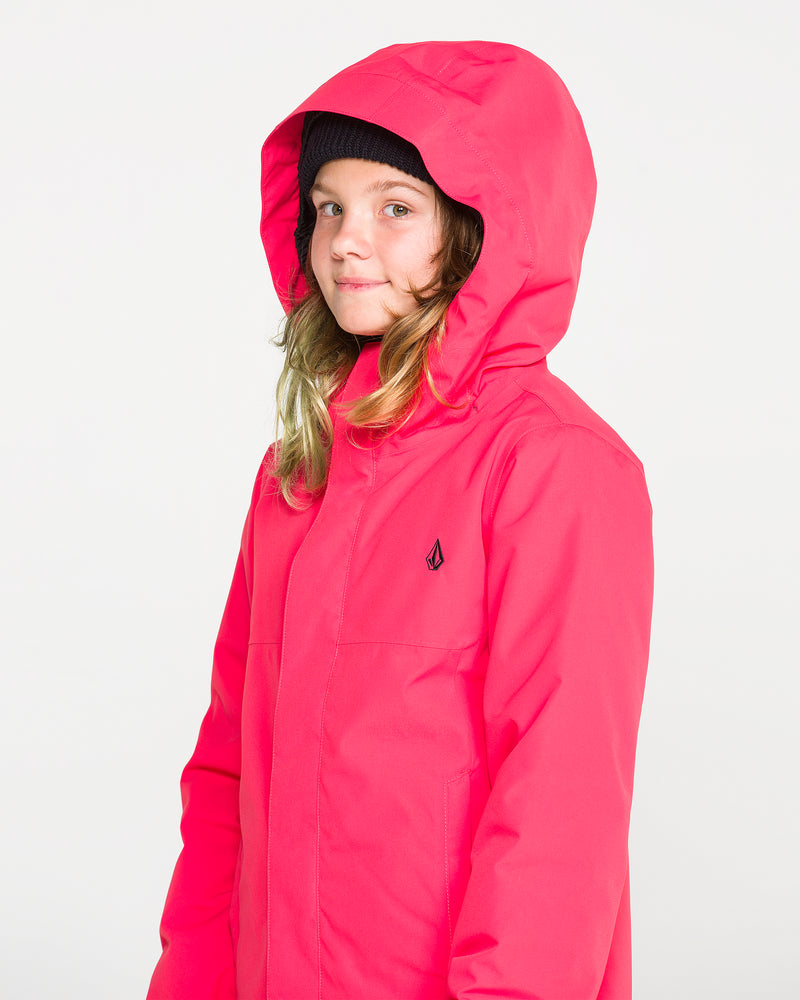 A young person with long hair wears the Volcom Kids’ Sass’N’Frass Insulated Jacket in bright pink, featuring a helmet-compatible hood and a black beanie, standing against a plain white background and looking at the camera with a neutral expression.
