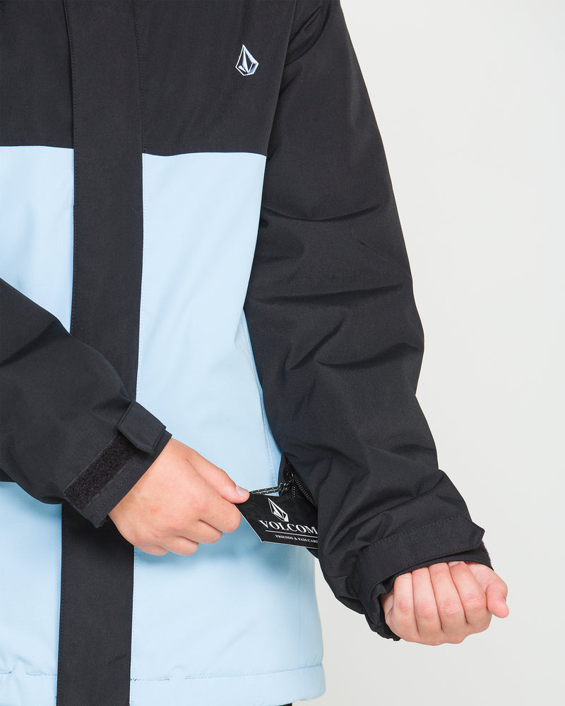 A person wearing the Volcom Kids’ Sass’N’Frass Insulated Jacket in black and light blue, made from recycled polyester, pulls on the sleeve to reveal a Volcom tag near the wrist. Only the jacket and their hands are visible against a plain background.