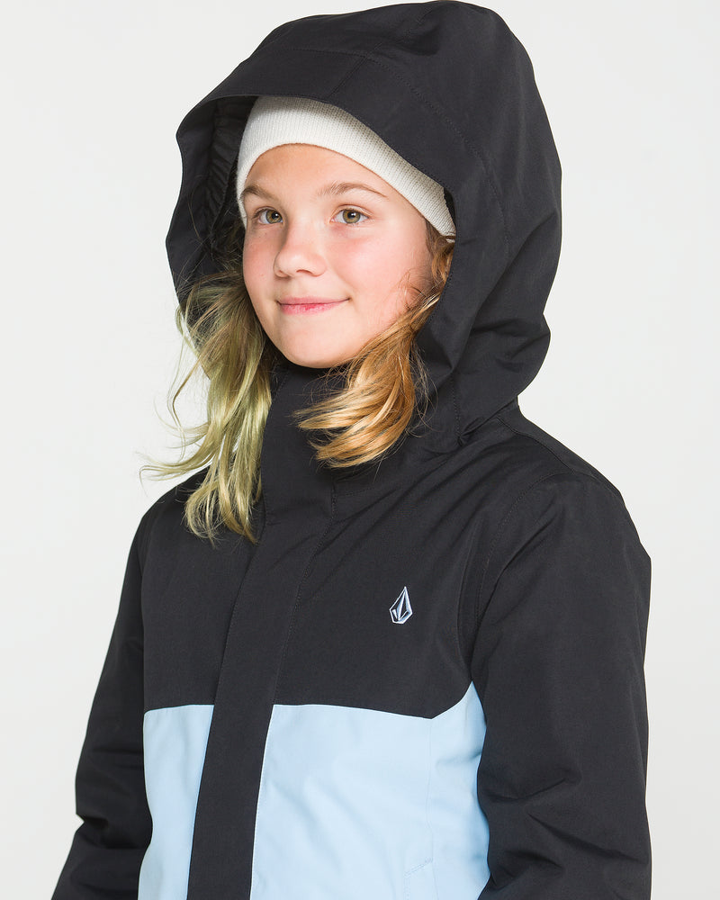 A young person wears the Volcom Kids’ Sass’N’Frass Insulated Jacket with the hood up and a white knit beanie, smiling slightly against a plain light background.