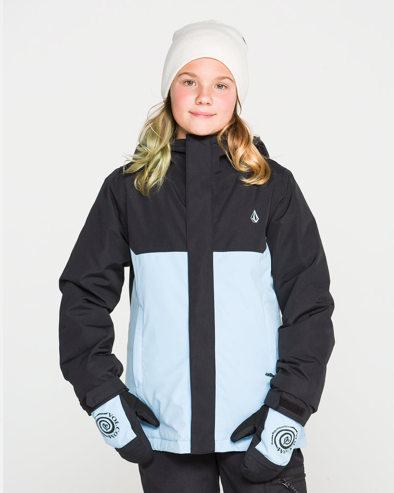 A young person wearing a white beanie, matching gloves, and the Volcom Kids’ Sass’N’Frass Insulated Jacket—crafted from recycled polyester with PFAS-free DWR in black and light blue—stands against a plain white background, looking at the camera with a slight smile.