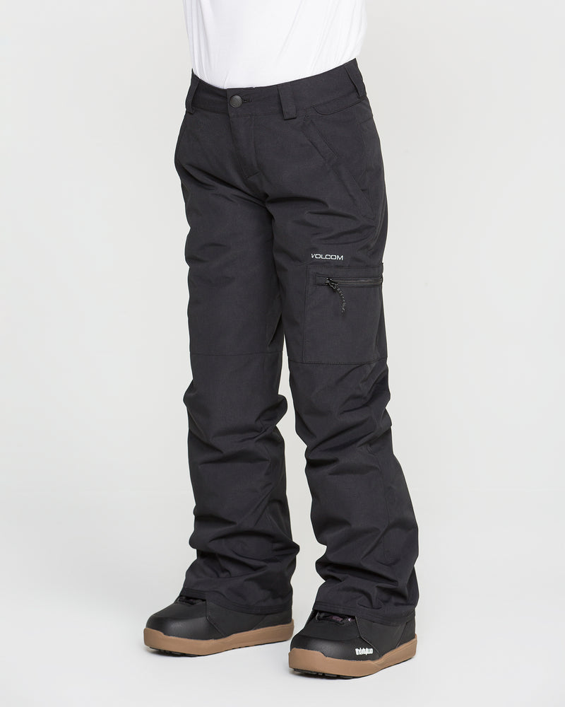 A person is wearing black Volcom Kids’ Frostique Insulated Pants, featuring an adjustable waist, along with black snow boots with brown soles. The image shows only the lower half of the body against a plain white background.