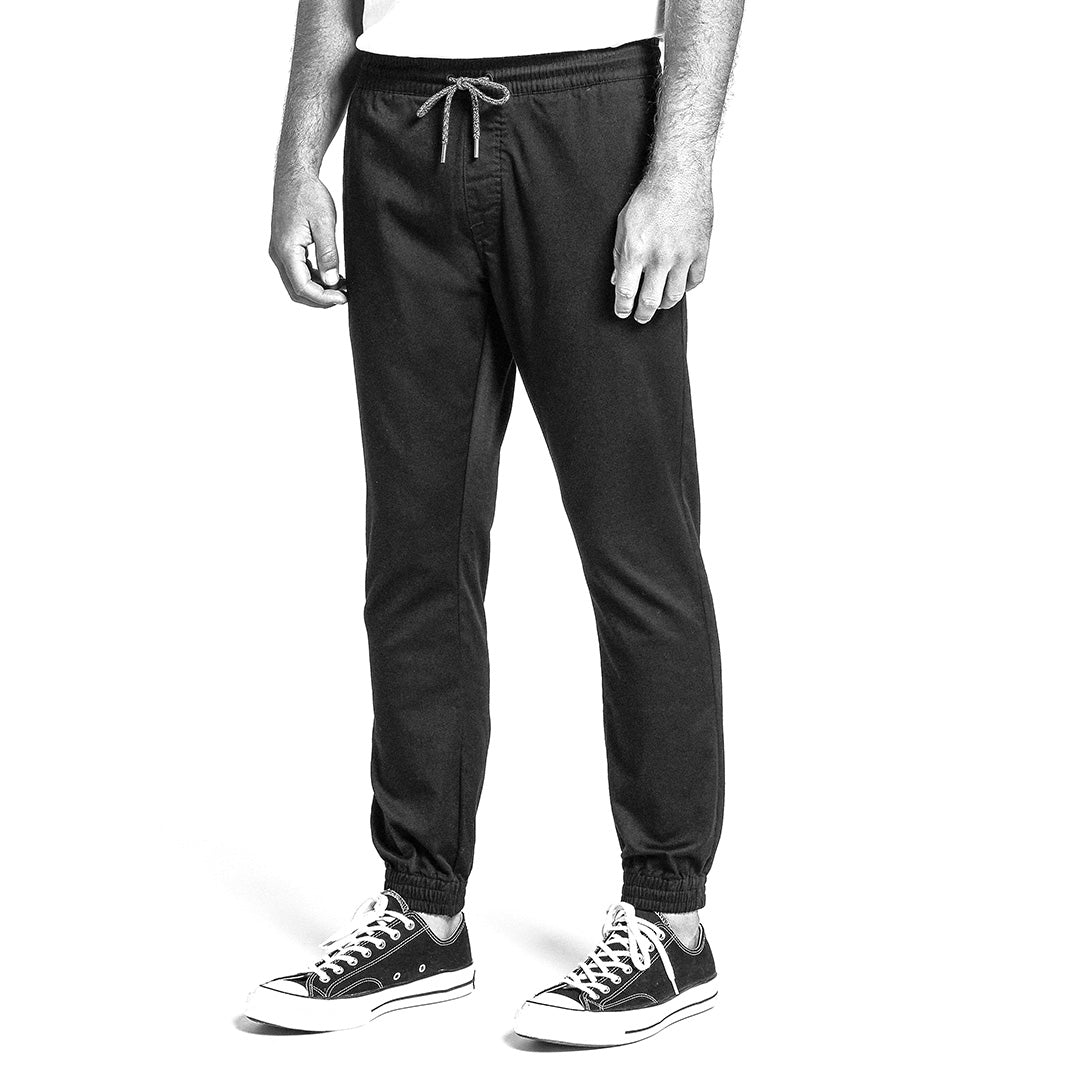 Black and white image of person wearing tapered pants and sneakers on a white background