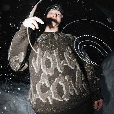 Person wearing a sweater with text, standing in a snowy landscape at night.