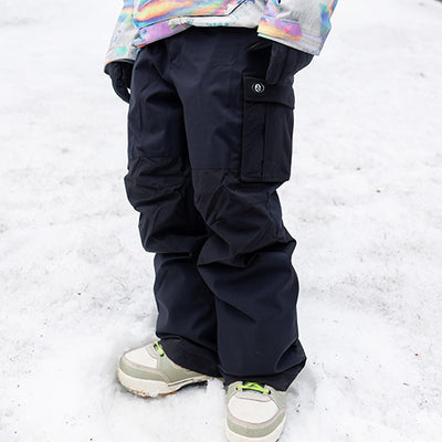 Person wearing dark snow pants and a colorful jacket in a snowy setting