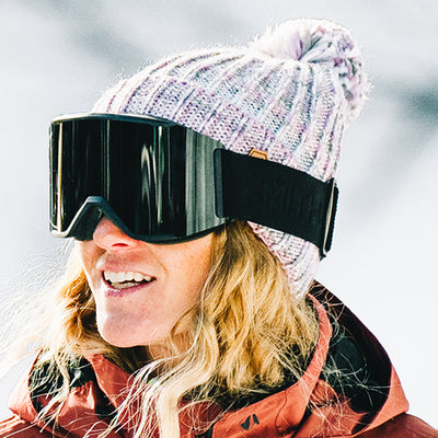 Person outside wearing sunglasses and a snow jacket with a beanie