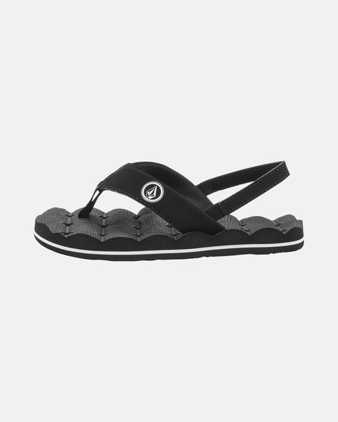 The Volcom Kids' Recliner 2 Little Youth sandal is black and gray with a textured wavy sole, comfort foam footbed, open toe, thong strap, supportive back strap, and a small circular logo on the side strap.