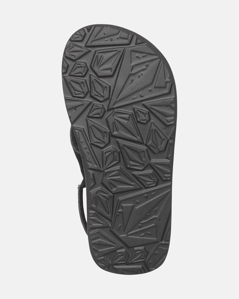 The image features the black rubber sole of the Volcom Kids' Recliner 2 Little Youth sandal, displaying a geometric, angular tread pattern for traction against a plain light gray background.