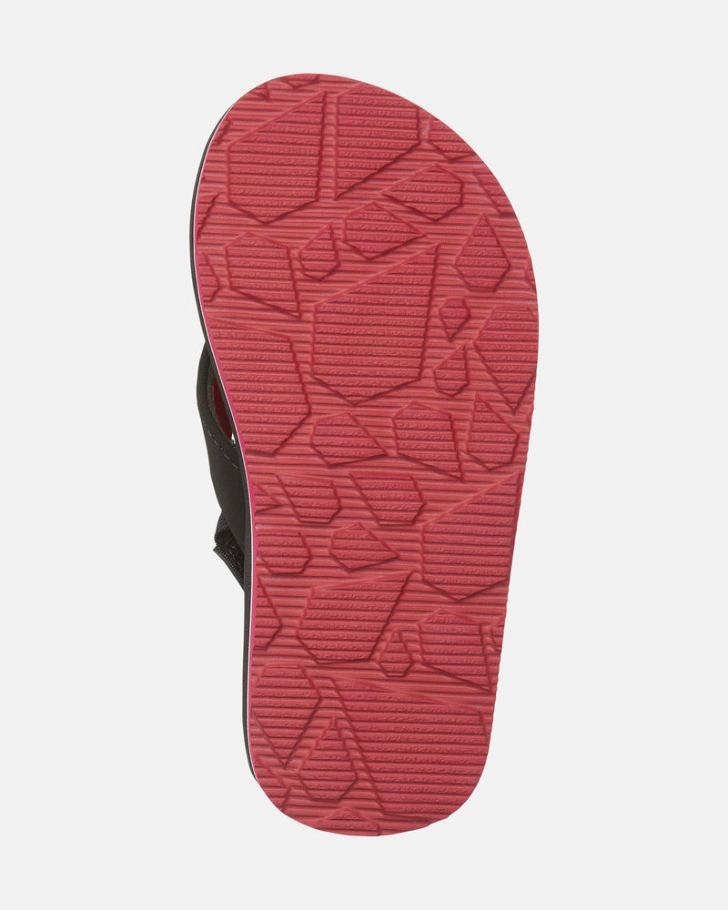 The image shows the red sole with a geometric, textured pattern of the Volcom Kids' Victor 2 Little Youth sandal. The mostly black upper is partly visible against a plain white background.