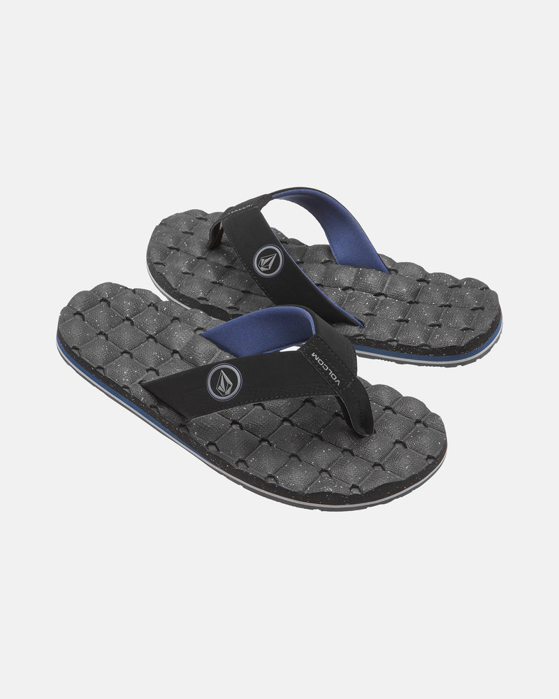 A pair of black Volcom Men's Recliner flip-flops featuring extra-grippy, textured woven-pattern soles and blue-lined straps, shown on a plain white background.