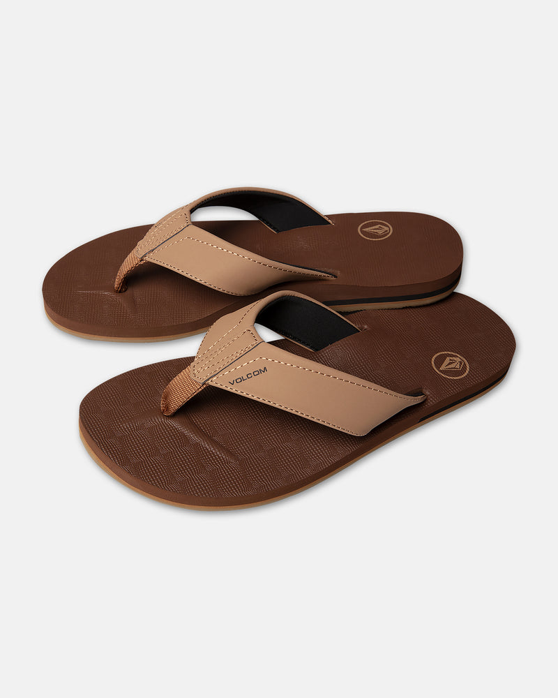 The Volcom Men's Victor flip-flop sandals feature thick straps, textured soles, and brown and tan coloring. Displayed on a white background, the Volcom logo appears on both the strap and footbed.