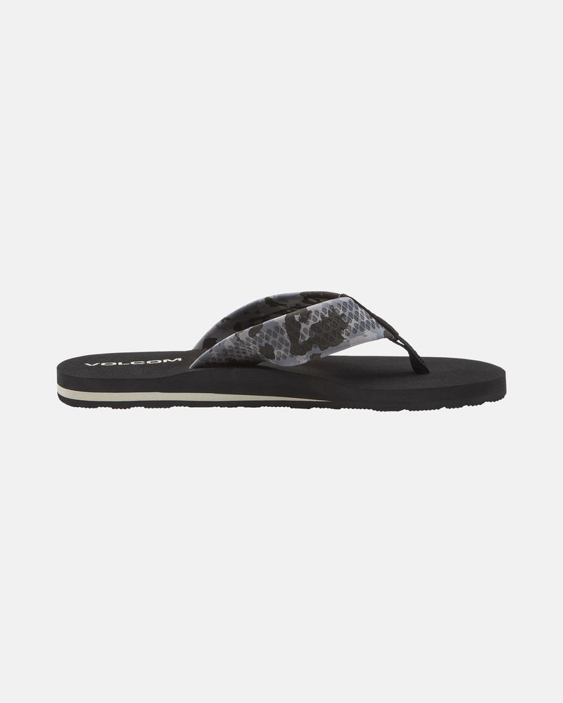 The Volcom Men's Daycation 2 sandal is a black flip-flop with a patterned grey and black fabric strap, cushioned EVA footbed, and molded rubber outsole, shown in side profile on a white background.
