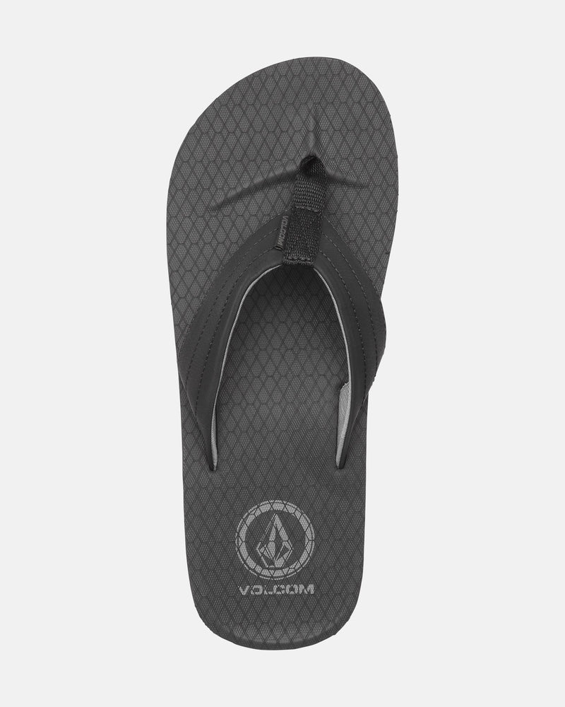 A top-view of the Men's Vol-Commuter Sandals by Volcom in black, featuring a textured footbed with a diamond pattern and the Volcom logo with text near the heel, displayed on a white background.