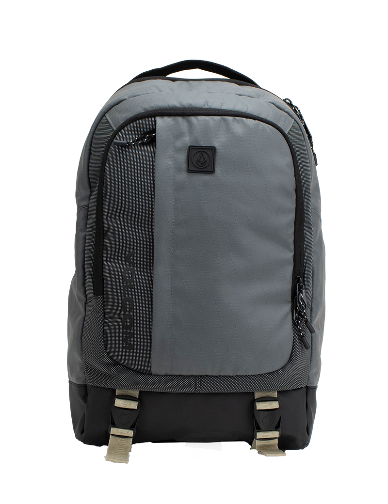 The Volcom Men's Venture Backpack features a gray design with a black bottom, front pocket, side zippers, and beige buckle straps. A small black logo patch accents the upper front. With a 22L capacity and padded laptop sleeve, this backpack offers a simple and functional style ideal for everyday use.