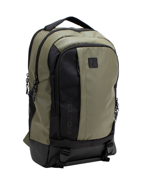 Introducing the Volcom Men's Venture Backpack in khaki and black, featuring a spacious 22L capacity with a front pocket, two side zippers, top handle, and a prominent black Volcom logo patch on the front. It includes a padded laptop sleeve for extra protection, a reinforced base for durability, and two bottom straps with buckles for added functionality.