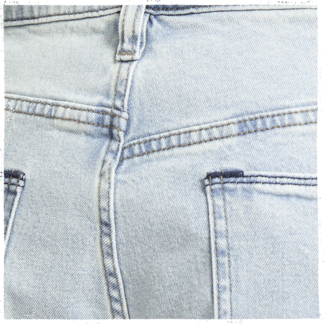 Close-up detail of the back waistband and pocket area of light-wash blue denim jeans, showing stitching and fabric texture.
