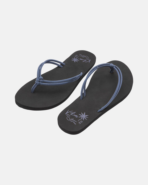 The Volcom Women's Forever And Ever II flip-flops feature black soles with thin blue straps and decorative writing plus palm tree graphics on the insoles, shown against a plain white background.