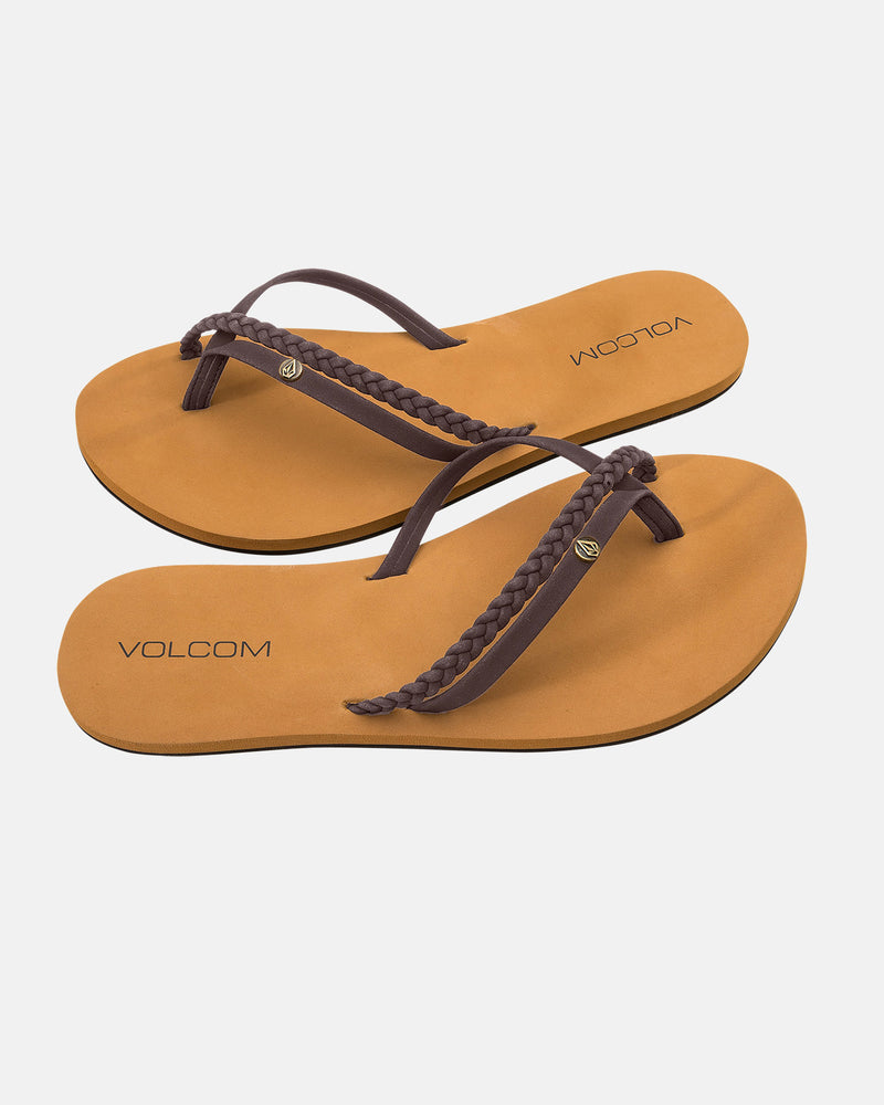 The Volcom Women's Thrills II flip-flops feature tan footbeds, brown braided synthetic leather straps, black logos, and molded arch support, shown on a white background.