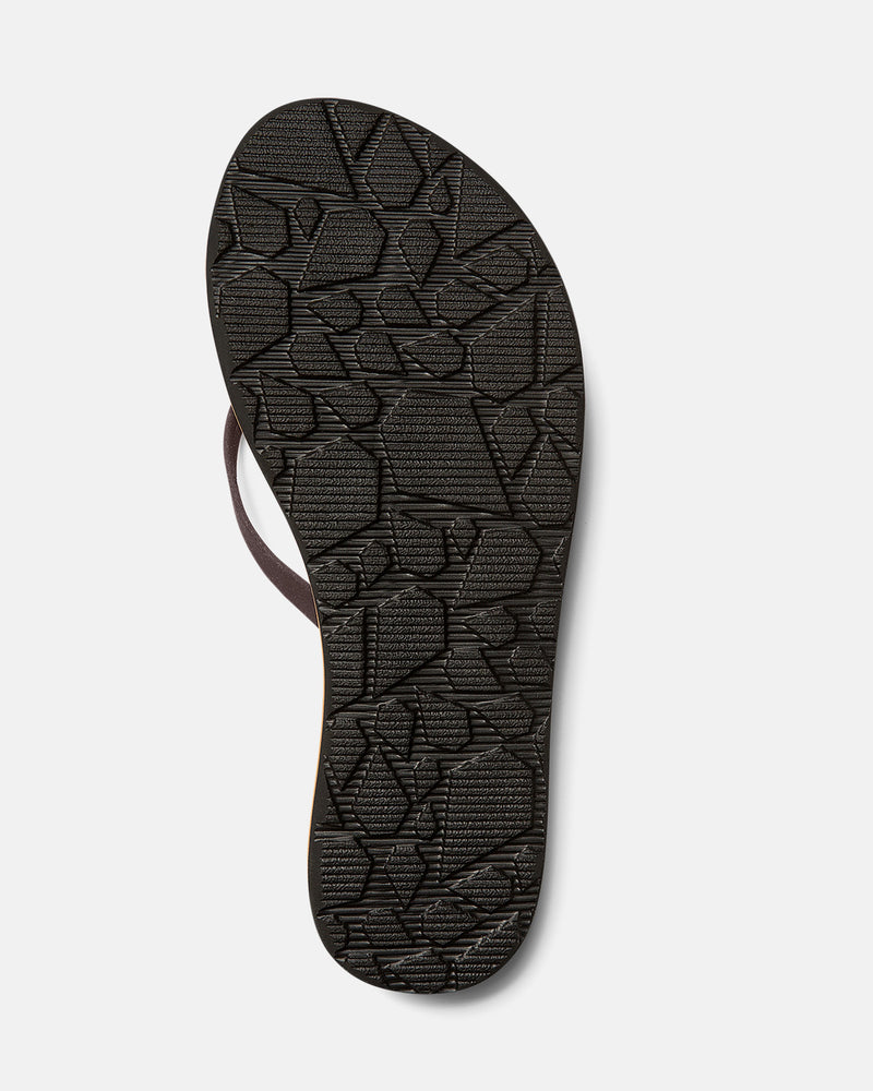 The image shows the sole of Volcom Women's Thrills II flip-flop sandal in dark brown with a textured geometric pattern and molded arch support, photographed against a plain light gray background.