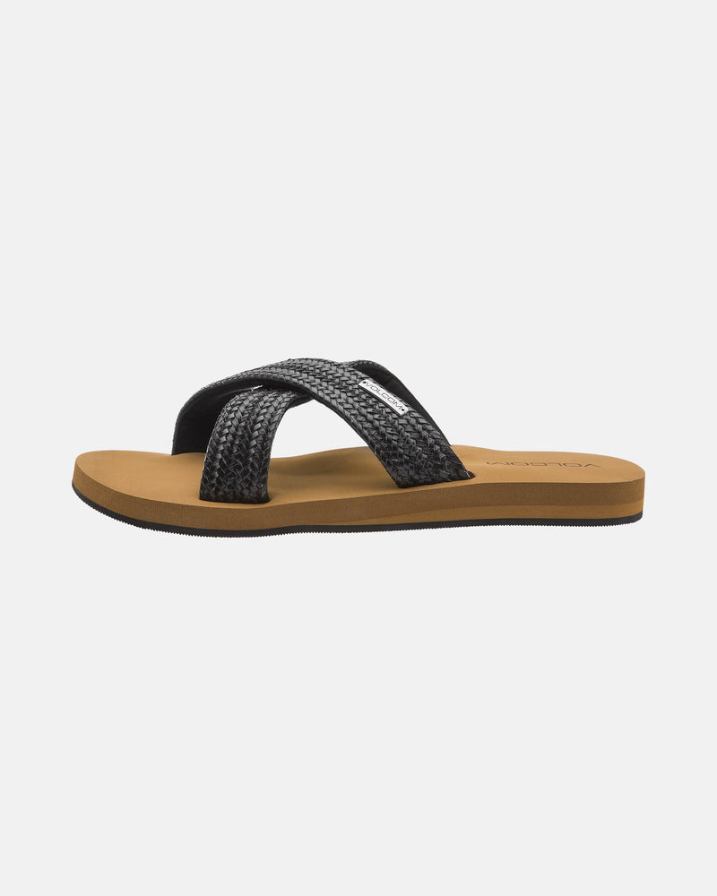 The Volcom Women's Double Cross Sandals feature a brown flat sole and black textured crisscross straps, shown from the side against a plain white background.