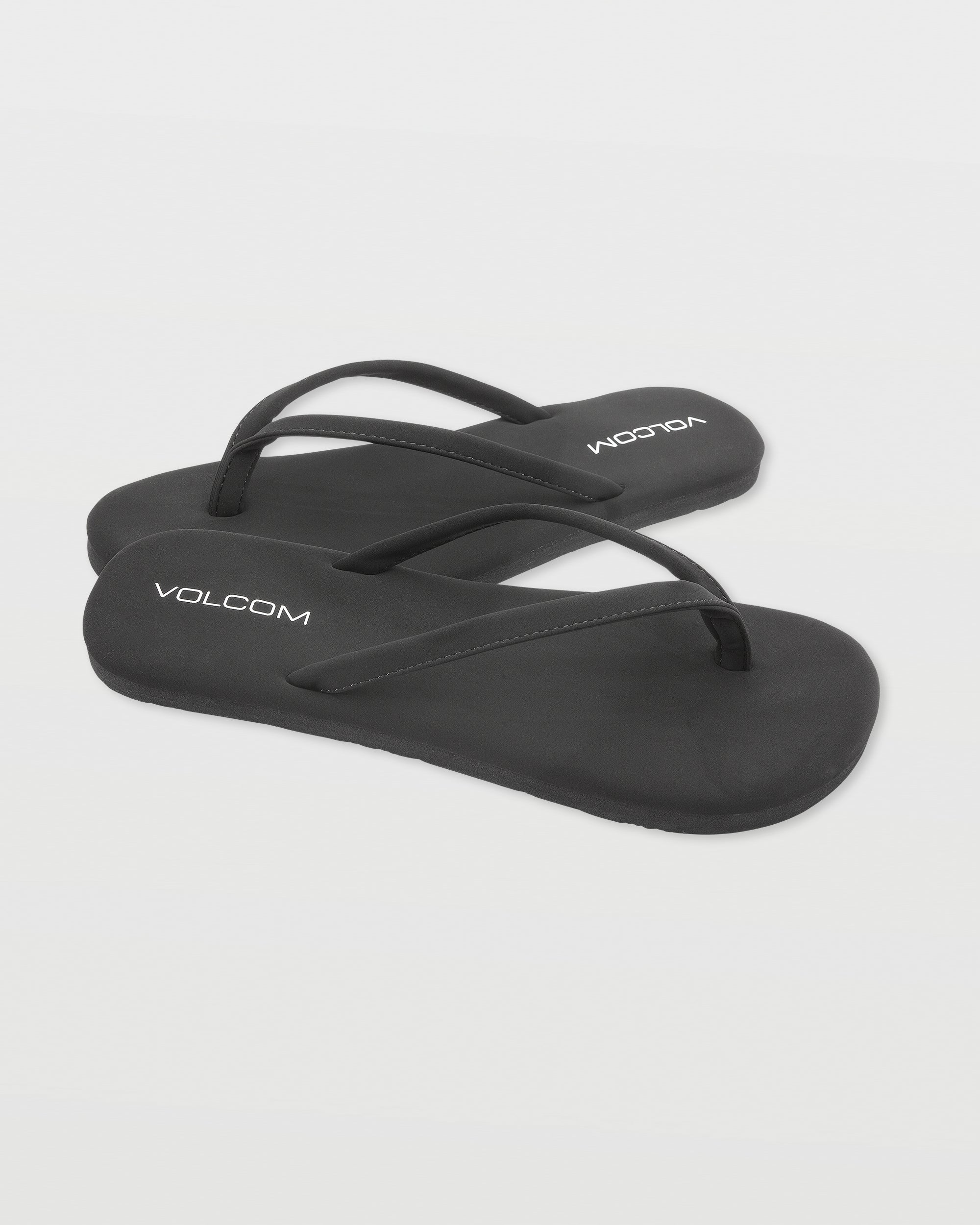 A pair of Women's Vibes flip-flops by Volcom in black with white branding on the footbeds, shown on a white background.