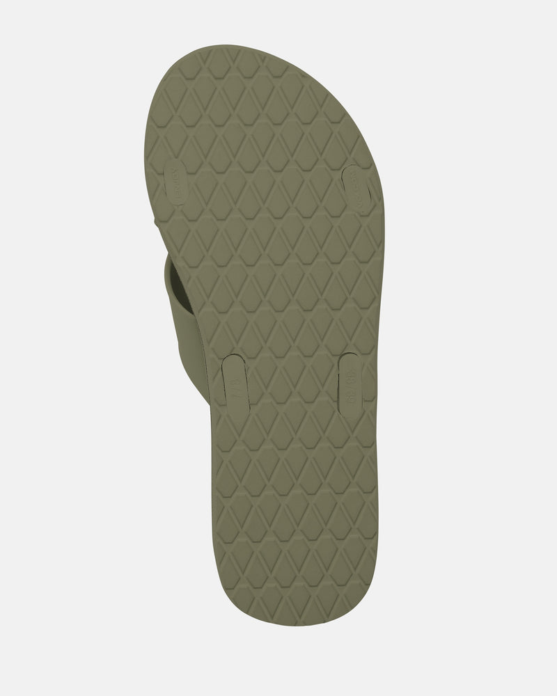 A Women's Volcomotion Strap Sandal by Volcom is shown from the bottom, revealing its green textured rubber sole with a diamond pattern and three circular plugs securing the straps against a plain white background.