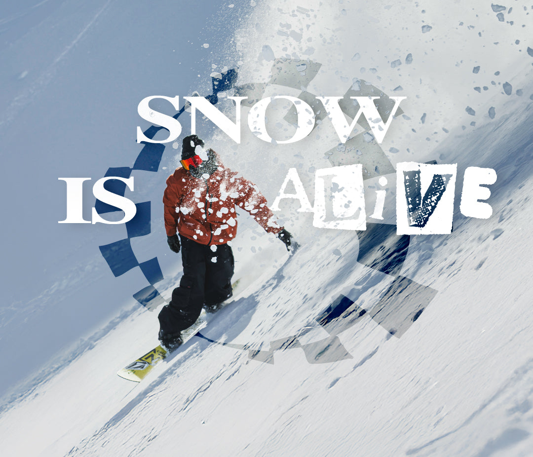 A snowboarder in a red jacket and black pants descends a snowy slope, with large overlaid text reading 'SNOW IS ALIVE' across the scene.