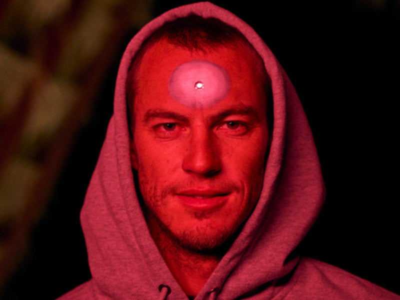 Person wearing a hooded garment with a red filter over their face.