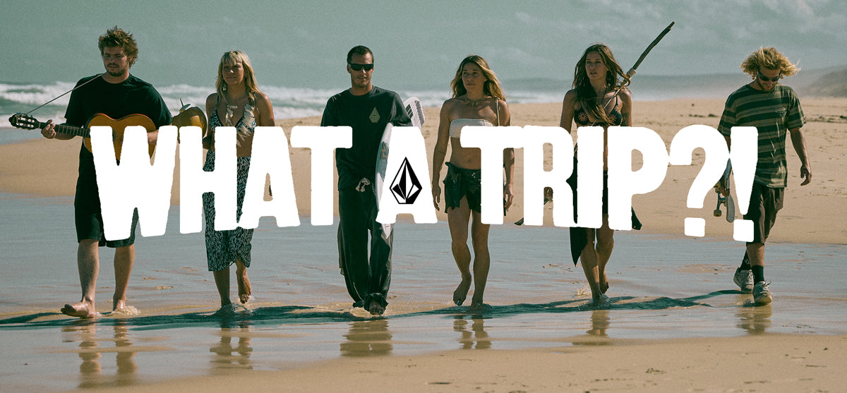 Group of people standing on a beach with 'WHAT A TRIP?!' text overlay