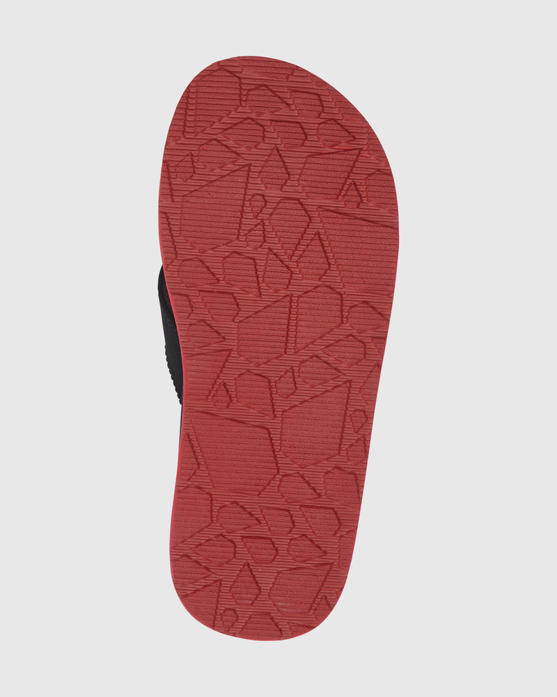 The image shows the bottom view of a red Volcom Kids' Victor Big Youth sandal sole with a geometric textured pattern. Only the sole is visible against a white background. The sandal offers a water-friendly footbed for enhanced comfort.