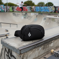Black waist bag on a concrete ledge at a skate park with graffiti in the background