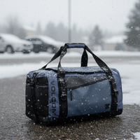 Blue duffel bag with black straps on a snowy street